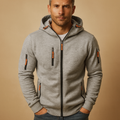 Man wearing a gray hoodie with orange accents on a beige background